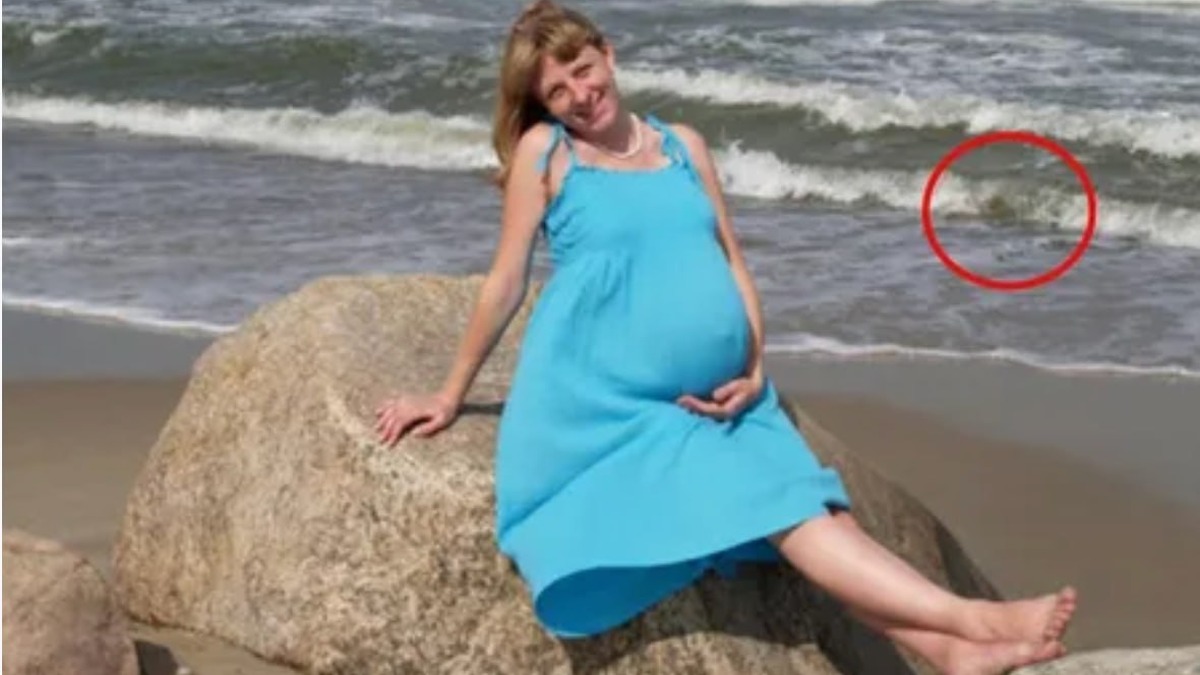 Pregnant woman sitting on a rock at the beach with a circled detail visible in the waves